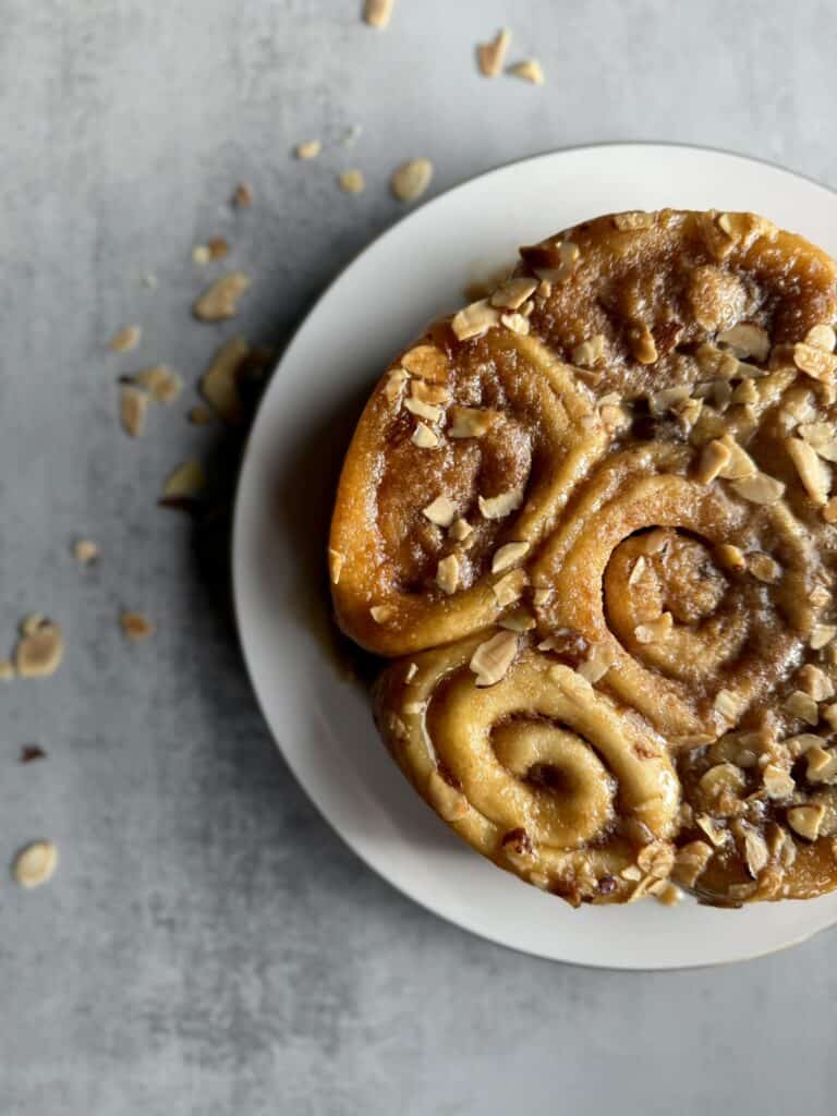 honey almond sticky buns on plate with toasted almonds surrounding