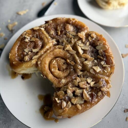 honey almond sticky buns with one missing and on a separate plate in the background with a fork