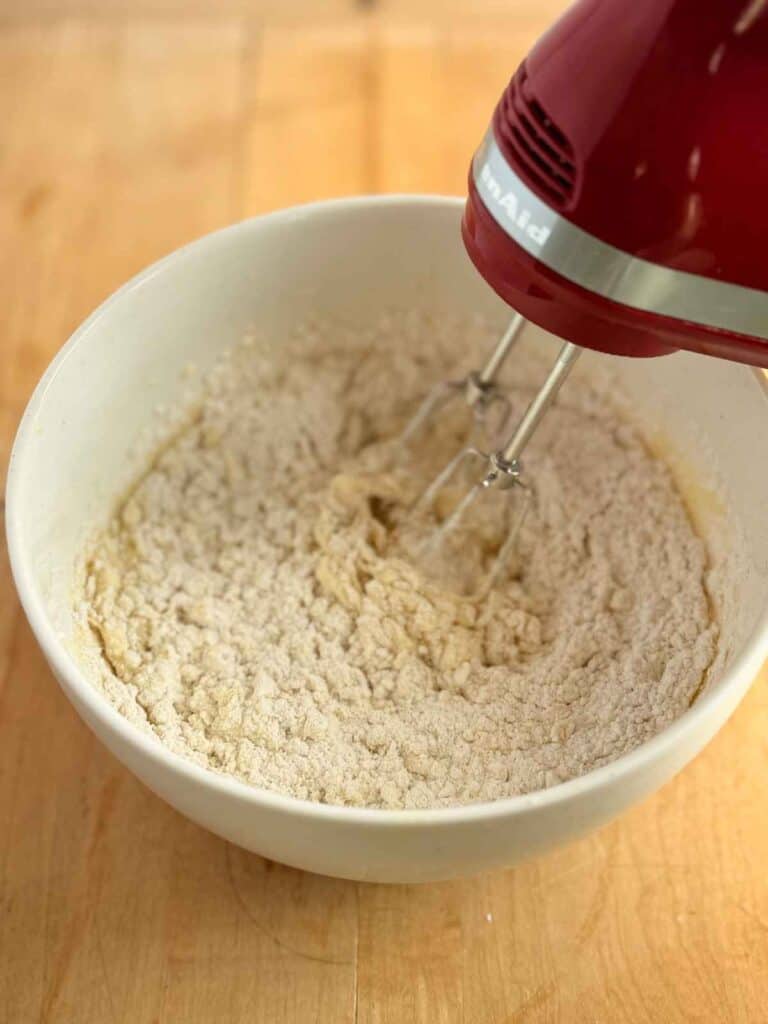 Adding second portion of dry ingredients to batter and mixing with hand mixer 