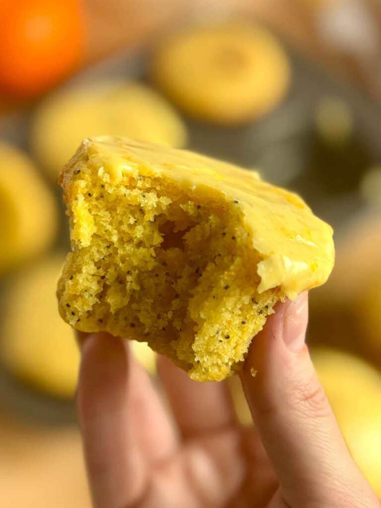 close up of orange poppy seed muffin with bite taken out 
