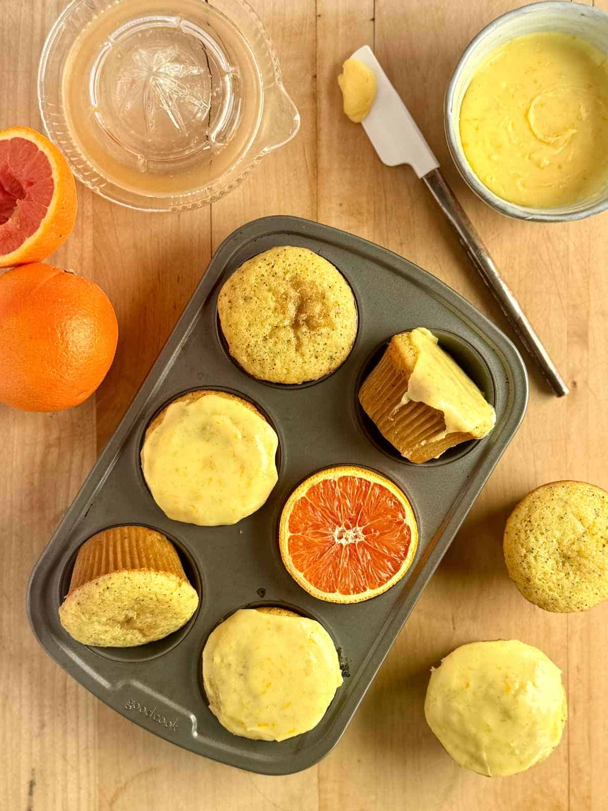 orange poppy seed muffins arranged in muffin tin with orange