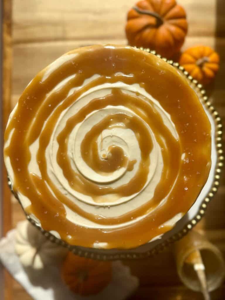brown butter pumpkin cake- OH cake on stand with butterscotch swirl on top and pumpkins in background