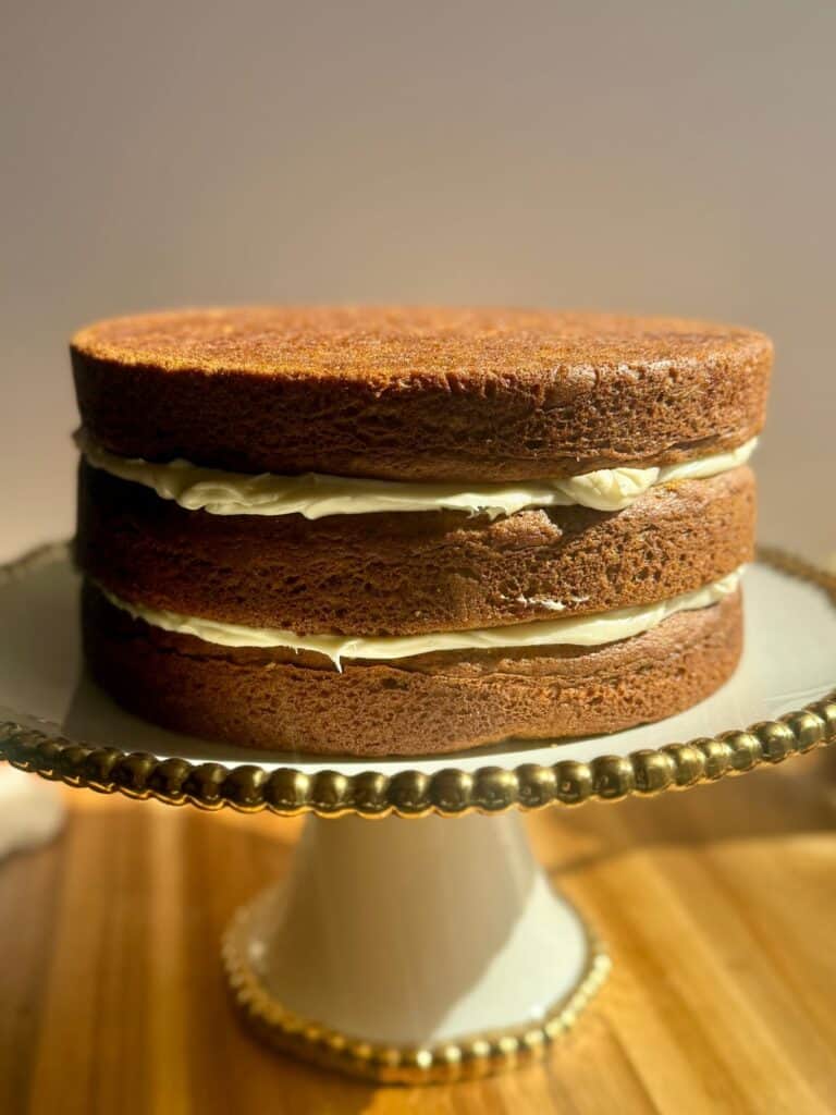 brown butter pumpkin cake- cake layers stacked unfrosted on cake stand