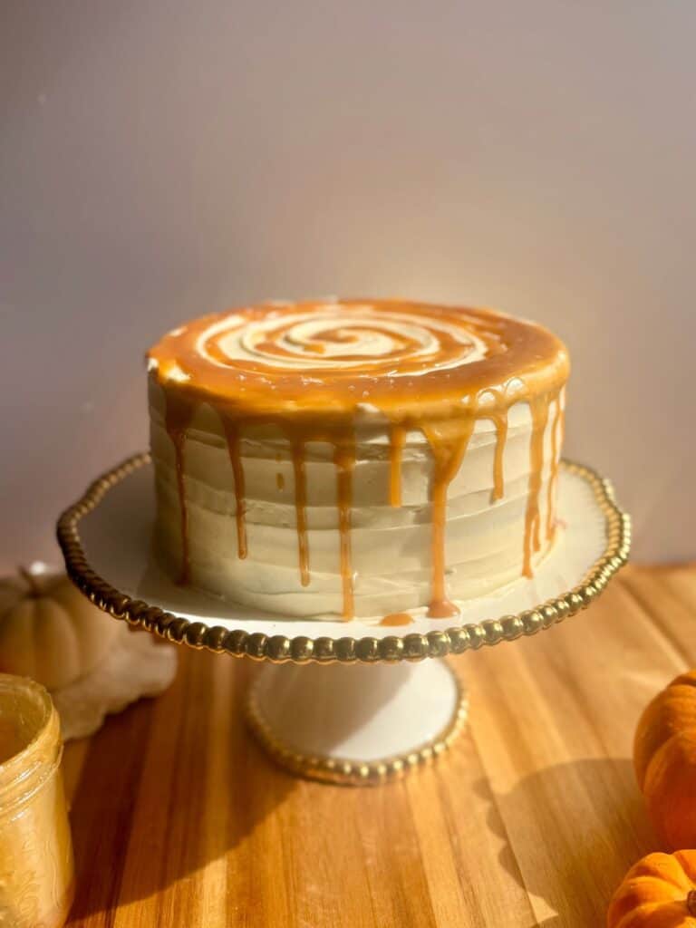 brown butter pumpkin cake- cake on stand with butterscotch dripping down sides