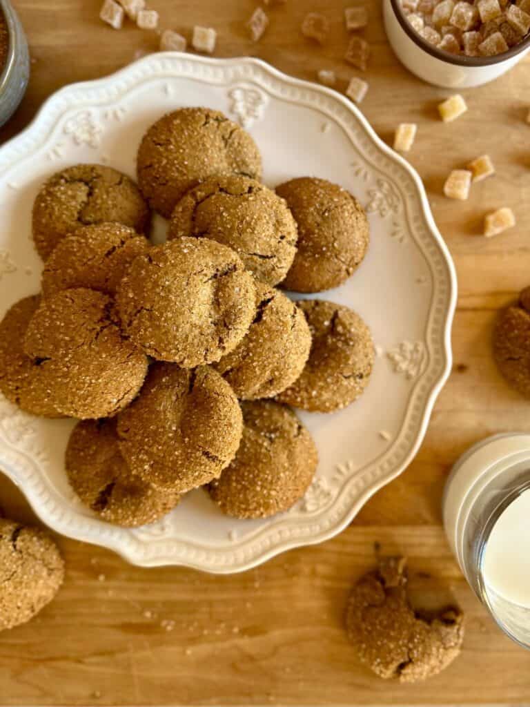 ginger molasses cookies - cookies stacked on white plate with ginger in corner and glass of milk 