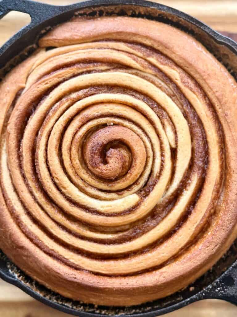 cast iron skillet cinnamon roll close up of golden brown swirl before iced