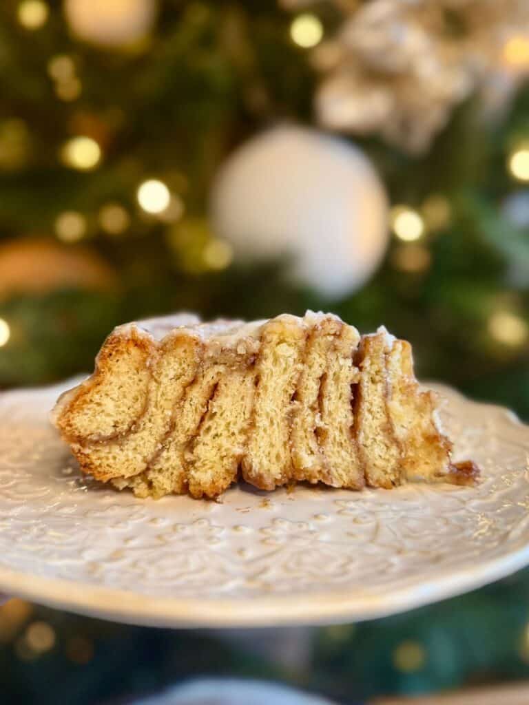 cast iron skillet cinnamon roll slice on plate showing layers with Christmas tree in background