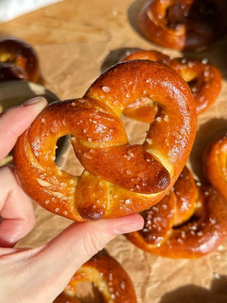 mini soft pretzels-close up holding golden buttery mini pretzel in hand