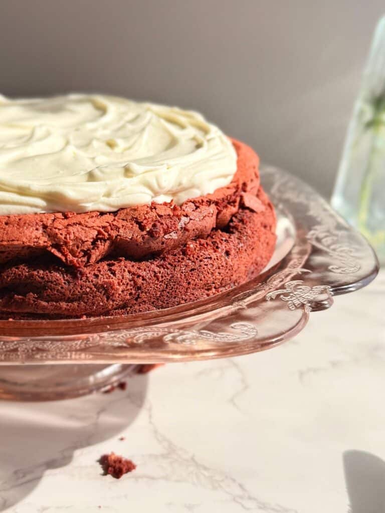 flourless red velvet torte with cream cheese whipped topping on pink cake showing crackly edges