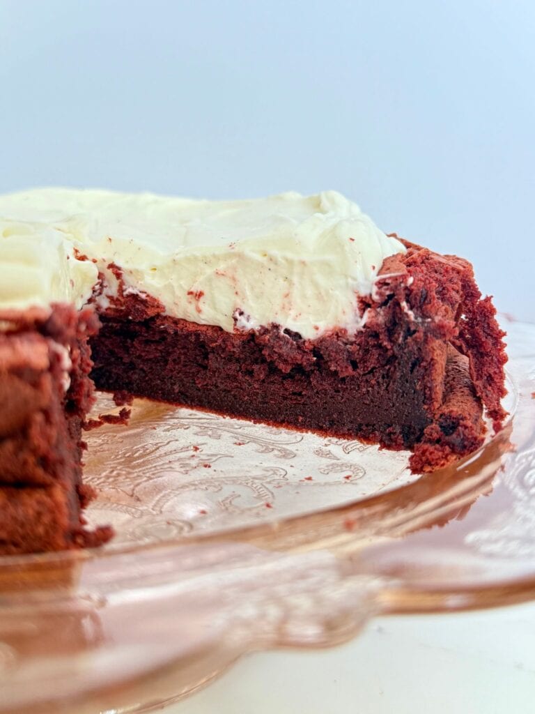 flourless red velvet torte with slice cut out showing the fudgy texture with light and creamy whipped topping