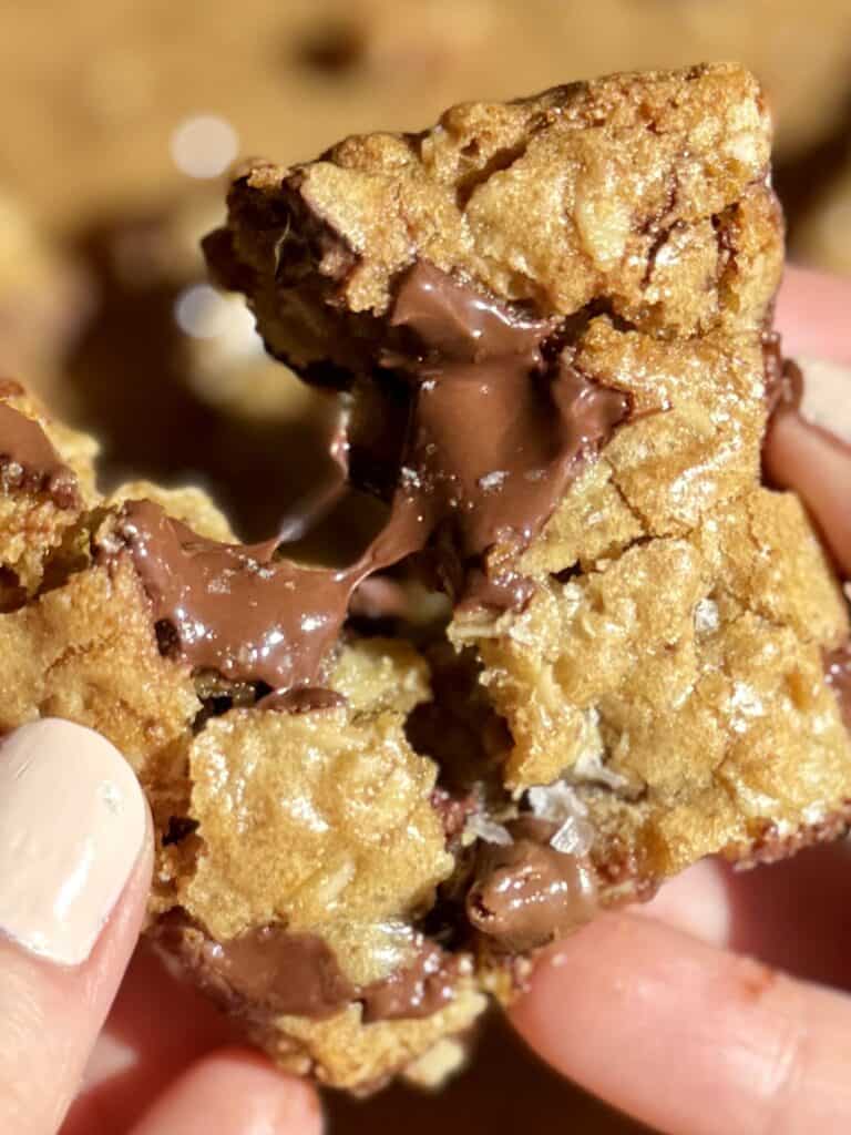 oatmeal chocolate chip cookie bar breaking in half with melty chocolate