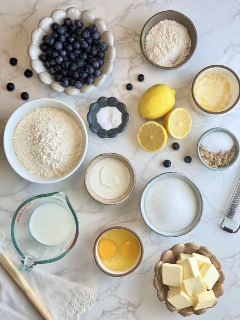 ingredients for lemon blueberry loaf cake arranged on marble background