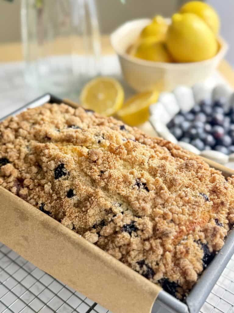 lemon blueberry loaf cake cooling in pan with crispy streusel on top