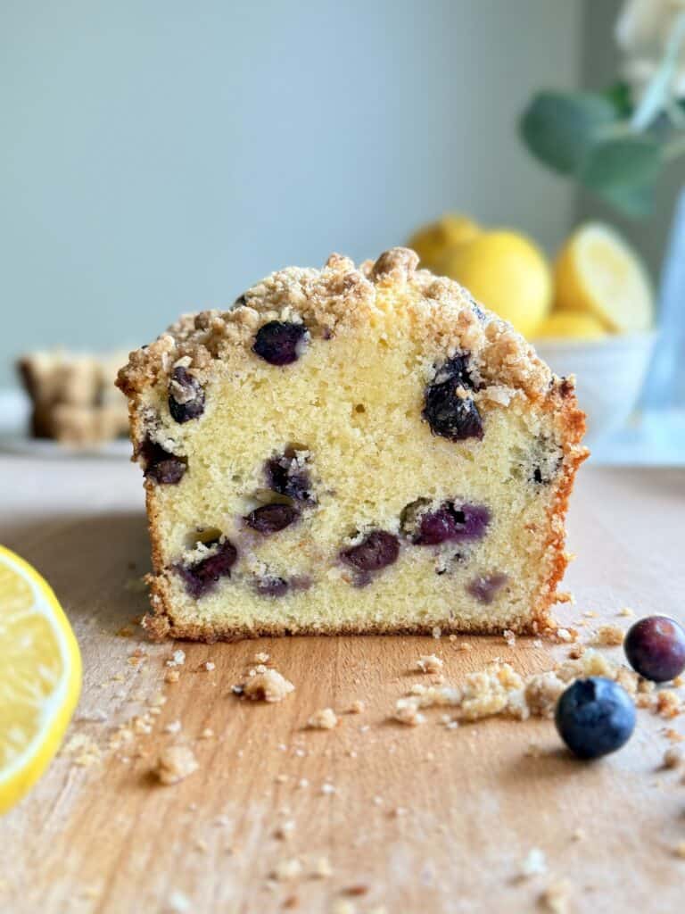 lemon blueberry loaf cake cut showing the soft moist center with lots of blueberries and streusel topping