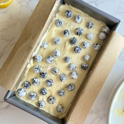lemon loaf cake layered with blueberries in pan