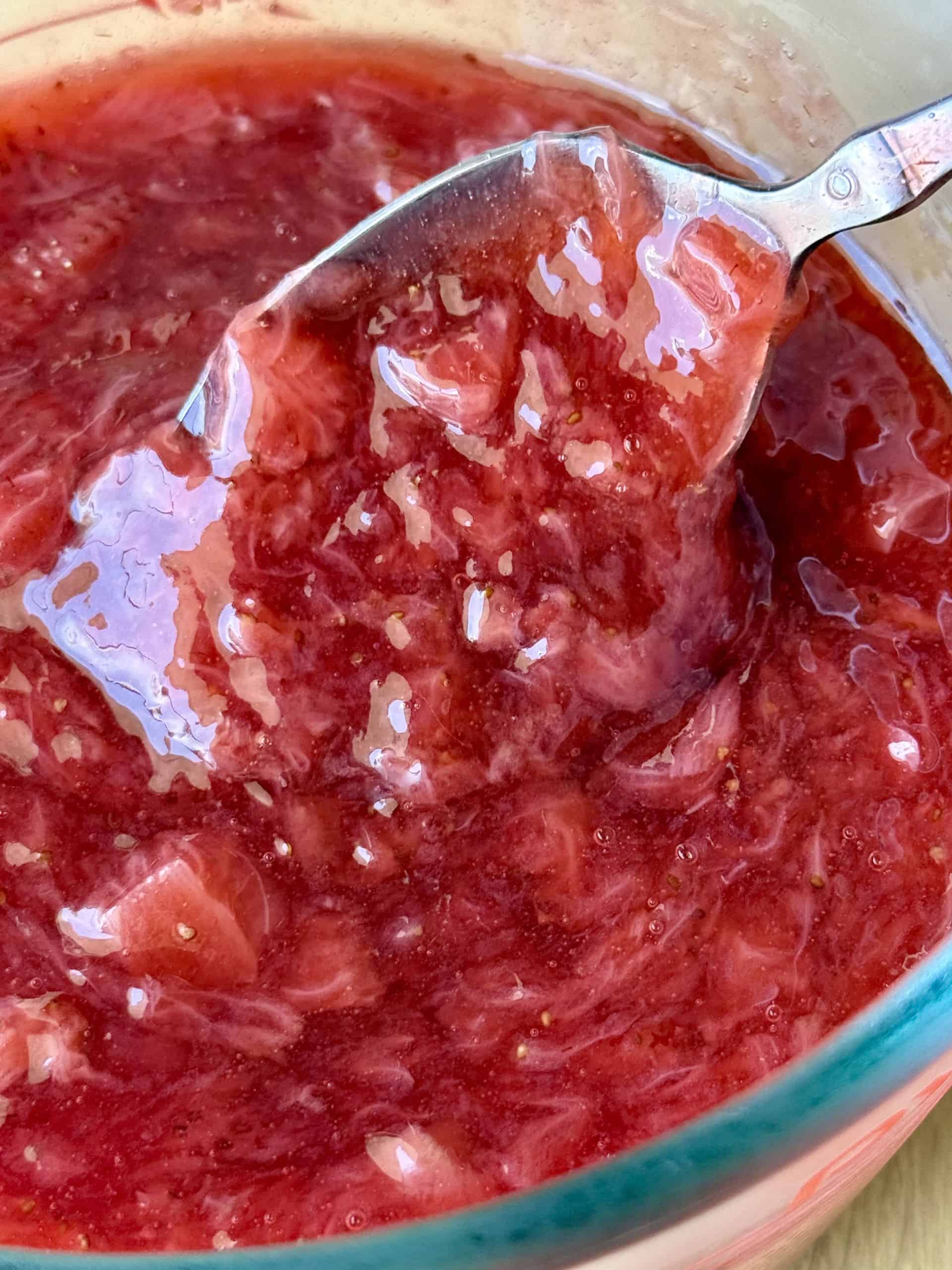 thick glossy strawberry jam filling in bowl for homemade strawberry cake