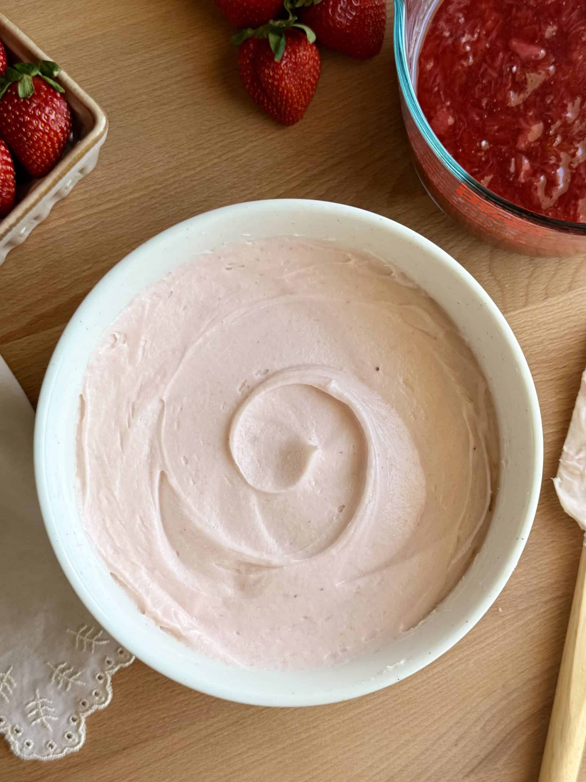 Creamy and smooth strawberry cream cheese frosting swirled in a mixing bowl