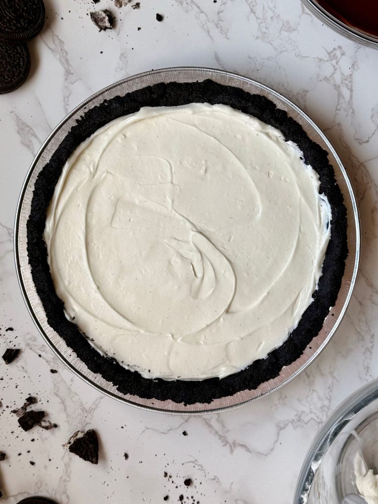 First layer of the triple layer Oreo cream pie showing the cream cheese filling spread in the Oreo crust