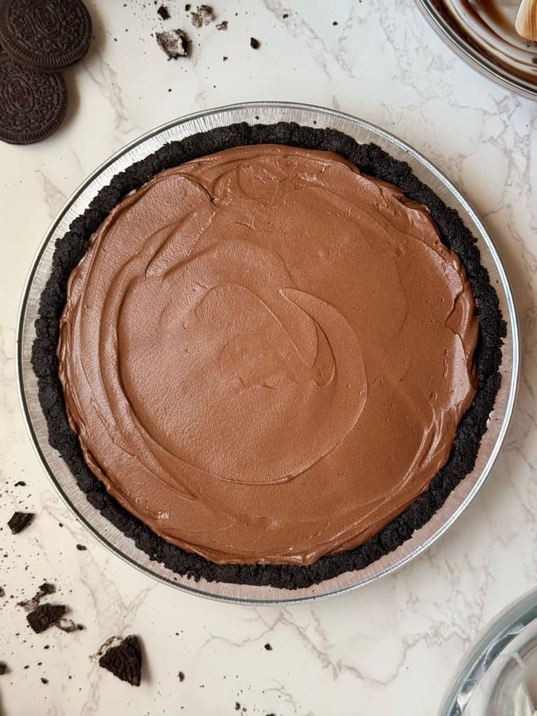 Second layer of the triple layer Oreo cream pie showing the whipped chocolate ganache smoothed into the pie