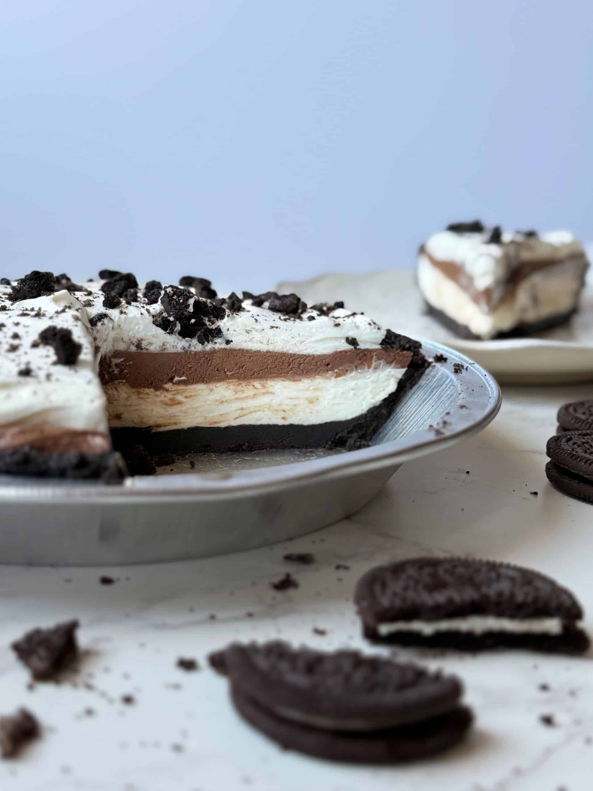Triple layer Oreo cream pie sliced into showing the cross section that displays the Oreo crust and the three distinctive layers of the pie