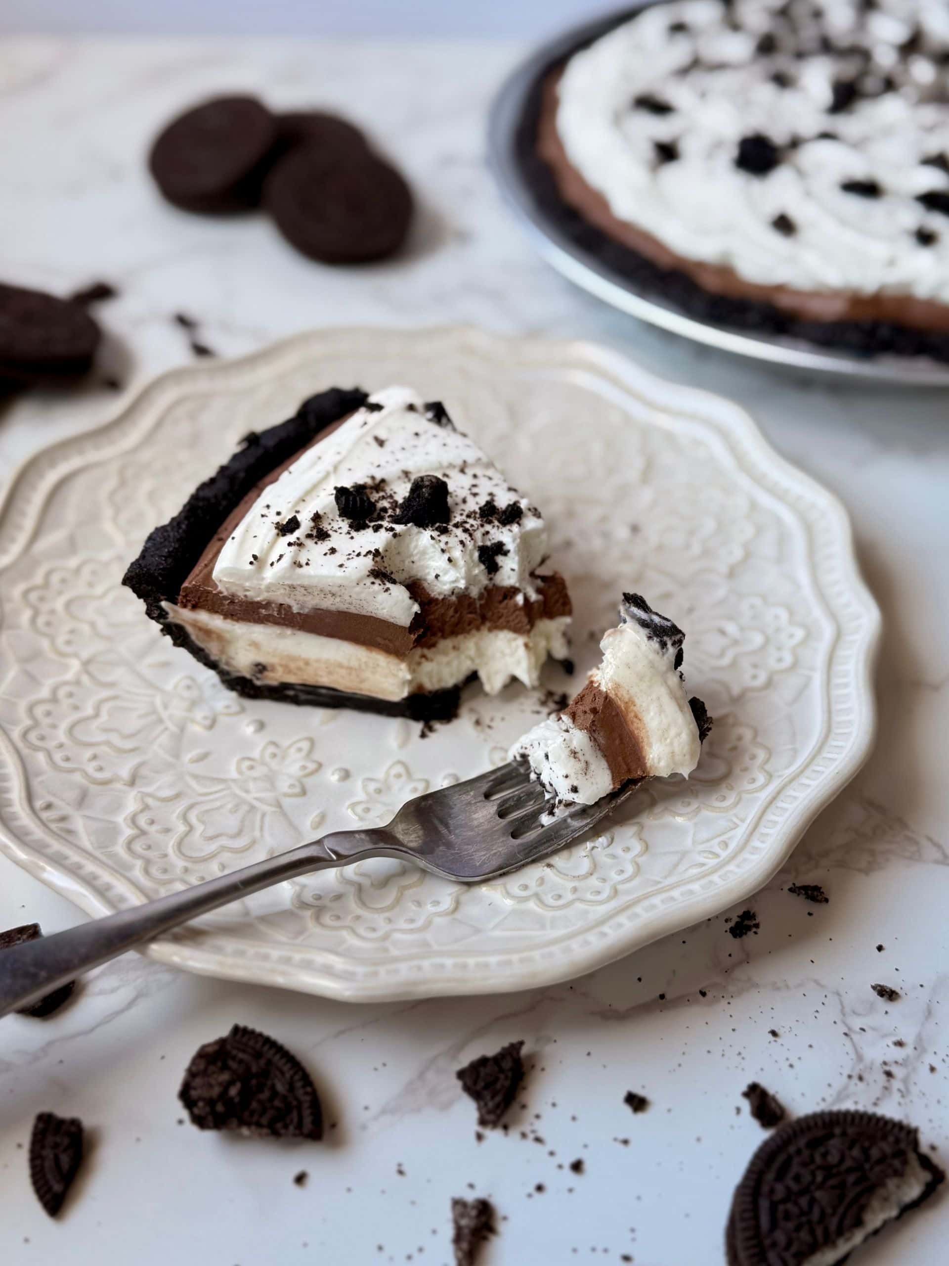slice of triple layer Oreo cream pie with bite taken out resting on fork 
