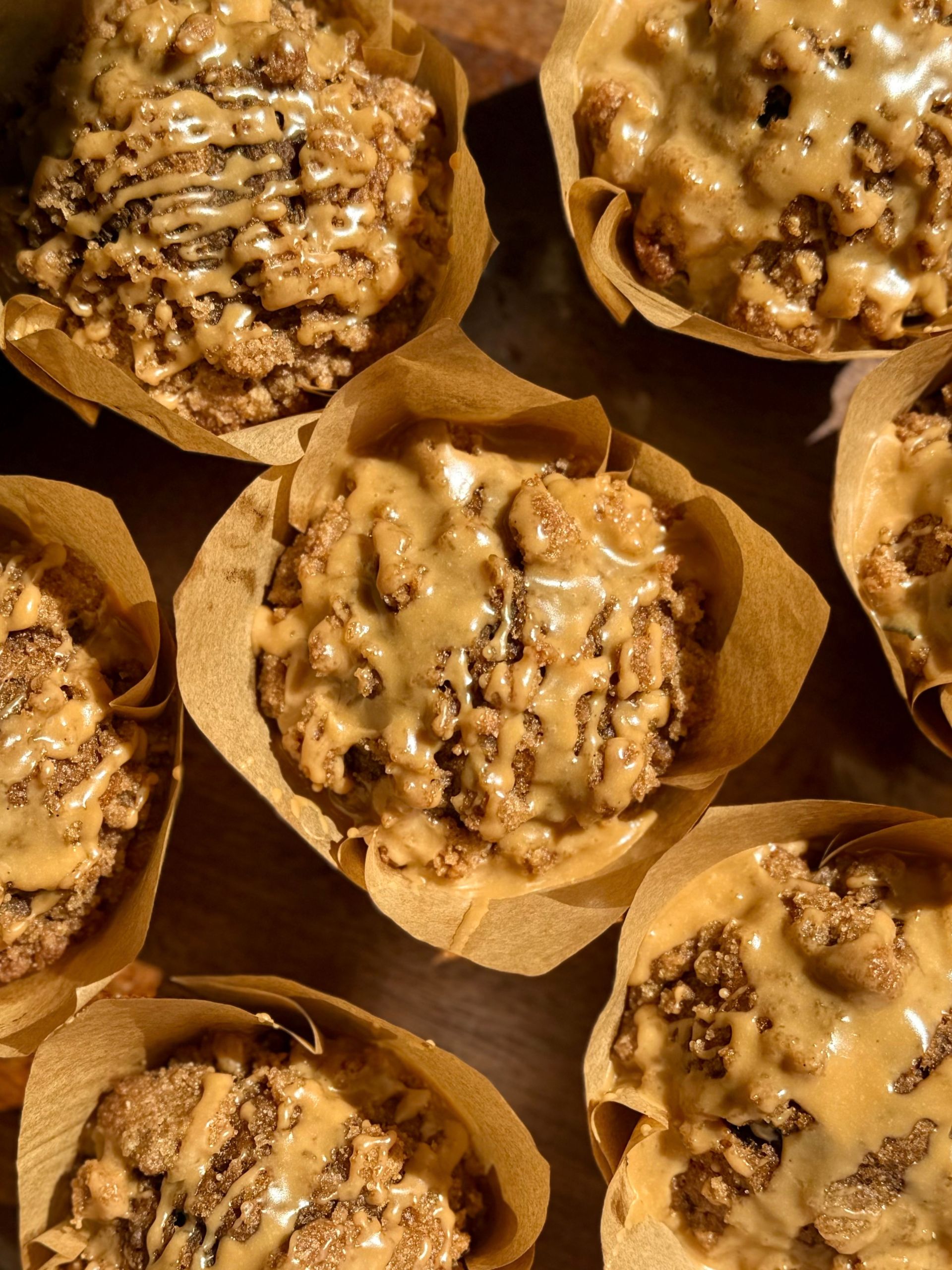 close up of golden pumpkin spice latte muffins in tulip muffin liners showing the crunchy streusel and espresso glazed drizzled on top 