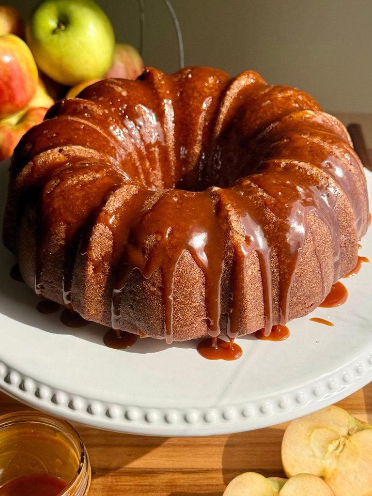 salted caramel apple bundt cake on cake stand with dripping caramel